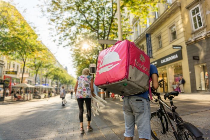 kuriér z firmy Foodora doručuje objednané jedlo